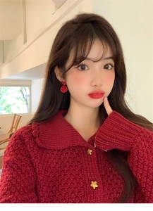 Close-up of model wearing red Fu character earrings with gold star button sweater