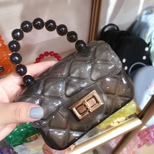 Detail of a black transparent PVC jelly bag with quilted pattern and bead handle