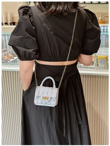 Close-up of light blue quilted jelly bag with gold chain strap worn by a model