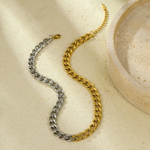 Two-tone gold and silver stainless steel Cuban link necklace on a stone background