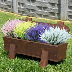 Outdoor wooden planter box with colorful artificial lavender shrubs on a green lawn