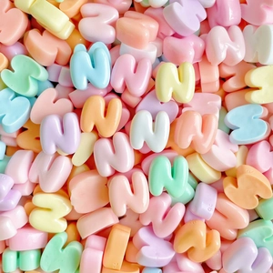 Macro detail of colorful heart-shaped resin beads featuring embossed letter N