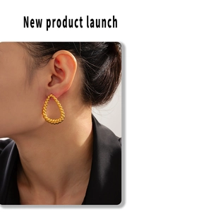 Detail of twisted gold-plated teardrop earrings showing unique texture on a model