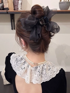 Macro shot of large black chiffon bow hair claw clip worn on a low bun hairstyle