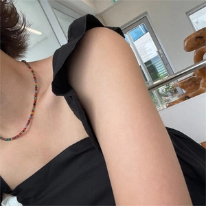 Close-up of a colorful beaded necklace worn with a black ruffled top on model