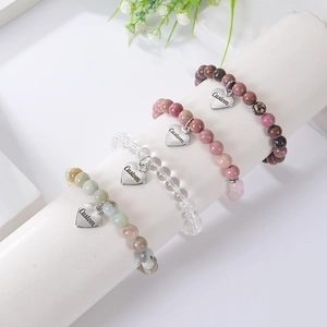 Detailed view of natural stone bead bracelets with customizable heart charms