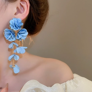 Detail of light blue chiffon flower tassel earrings worn by a model in soft lighting