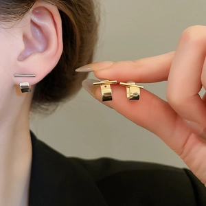 Detail view of minimalist geometric earrings in gold and silver finish on a model's ear