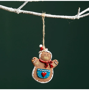 Detail of a resin gingerbread man ornament with red scarf hanging from a rustic branch