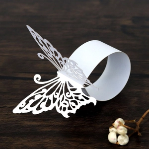 Detailed laser-cut white butterfly paper napkin ring on dark wood table background