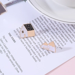 Detail of French house and mountain enamel brooches on a book background with gold plating