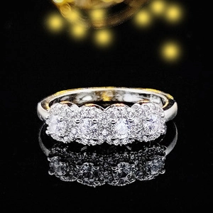 Detail of four cluster flower zircon rings on black reflective mirror surface