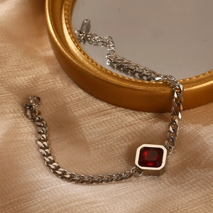 Detail eines silbernen Panzerarmbands mit quadratischem rotem Zirkon auf goldenem Seidenstoff