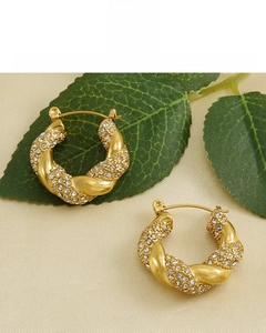 Macro detail of 18k gold plated twisted hoop earrings with sparkling pave zircon settings