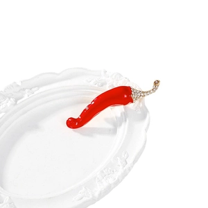 Artistic red chili pepper brooch with sparkling rhinestones on a white carved plate