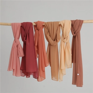 Chiffon solid color headscarf shawls for women in multiple warm tones hanging on a bar