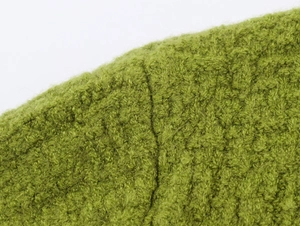 Close-up of grass green knit fabric showing textured plush yarn and durable seam