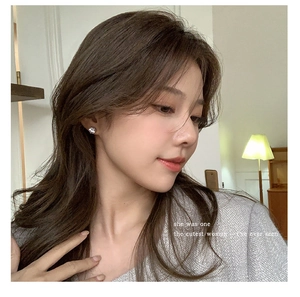 Close-up of sparkling cubic zirconia round stud earring on model in warm lighting