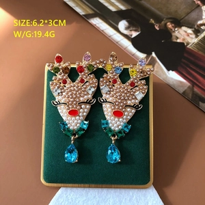 Christmas reindeer drop earrings with pearls and colorful crystals on green velvet