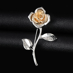 Close-up of vintage rose brooch with gold flower head and silver metal leaves