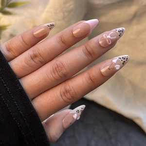 Detail of almond press on nails with leopard french tips and 3D pearl accents