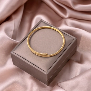 Detail of gold twisted metal cuff bracelet displayed on a premium jewelry gift box