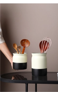 Close-up of black and white ceramic cutlery holder set with kitchen utensils and tools