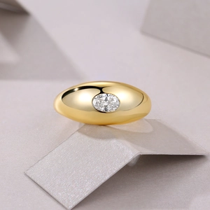 Macro shot of chunky gold dome ring featuring an oval-cut moissanite stone setting