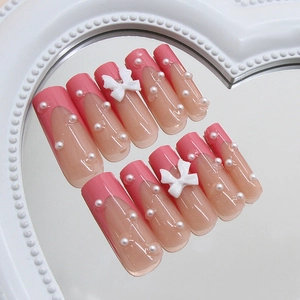 Sweet pink French press-on nails with 3D bows and pearls on a heart-shaped mirror