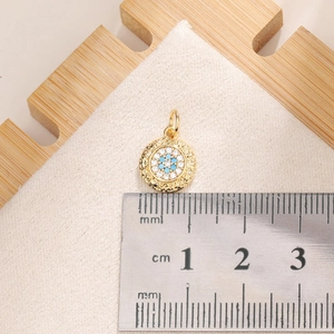 Macro view of a 1.1cm gold Evil Eye pendant with blue zircon stones next to a ruler