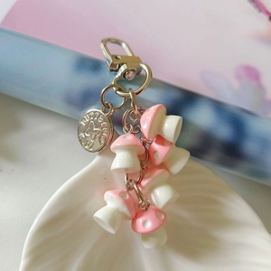 Close-up of cute pink and white resin mushroom charms with a silver metal clasp in a shell dish