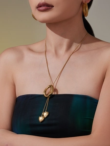 Detail of gold heart pendant necklace and textured earrings set on a female model