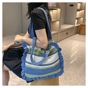 Detail of hand-woven striped knit tote bag with blue and green wavy ruffled edges