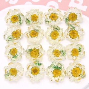Daisy resin charms in a white plate for DIY earrings and hair accessories on pink background