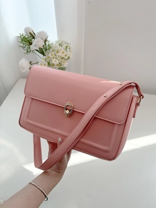 Detail of a pink glossy leather shoulder bag with an elegant golden interlocking buckle