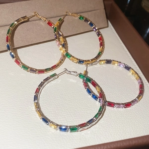 Macro view of colorful zircon hoop earrings with gradient crystal inlays in gold plating