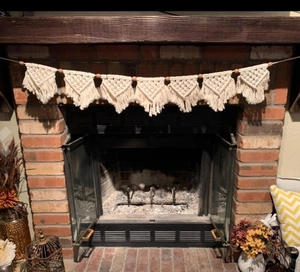Close-up of Bohemian handwoven cotton banner with tassels and wooden beads over fireplace