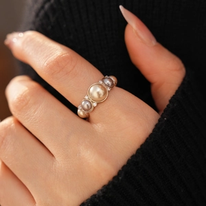 Detail of vintage ring featuring gold and grey pearls with zircon accents on hand