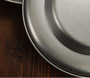 Macro detail of vintage style stainless steel soup plate with textured matte finish