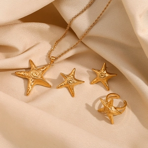 Gold starfish jewelry set with necklace earrings and ring on beige silk background