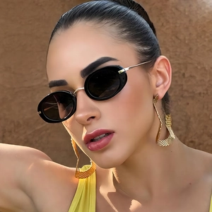 Retro oval black sunglasses and oversized gold textured earrings on a fashion model