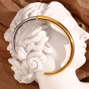 Artistic detail of gold and silver mixed-metal open bangle on a white bust statue