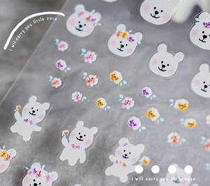 Macro shot of ultra-thin floral and cream bear nail art stickers on a textured surface