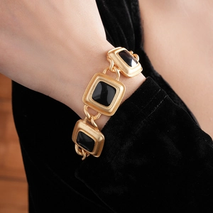 Detail view of vintage gold square link bracelet with black enamel inlay on model wrist