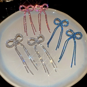 Detailed close-up of bow tassel earrings with sparkling rhinestones in three colors