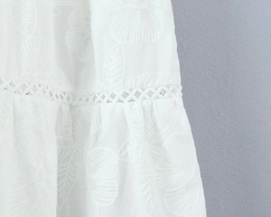 Gros plan détaillé des broderies florales blanches et motifs ajourés géométriques