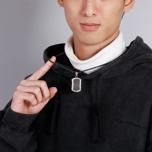 Close-up of a men's stainless steel military tag pendant on a black braided cord chain