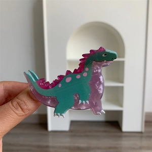 Detail of green acrylic dinosaur hair claw with pink dots and sturdy metal spring