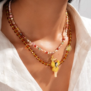 Detail of layered beaded necklace with butterfly and fairy resin charms on model