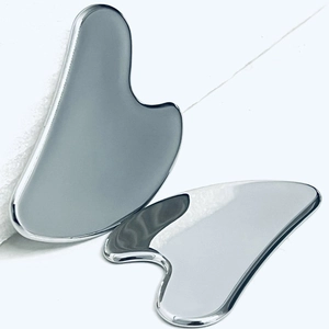 Outils de massage facial Gua Sha en acier inoxydable 304 poli sur fond blanc épuré